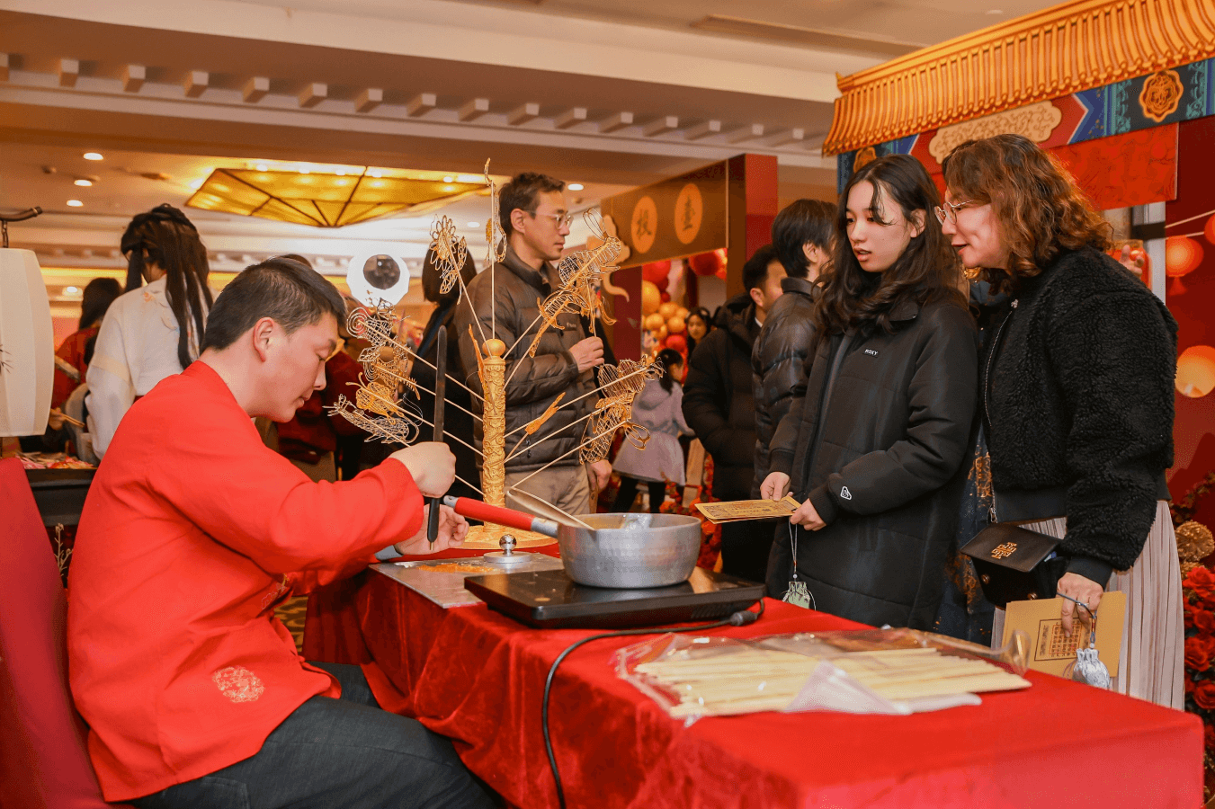 A skilled artist demonstrates the intricate craft of sugar painting, one of the immersive “Jianghu Market” activities designed to welcome and delight guests.