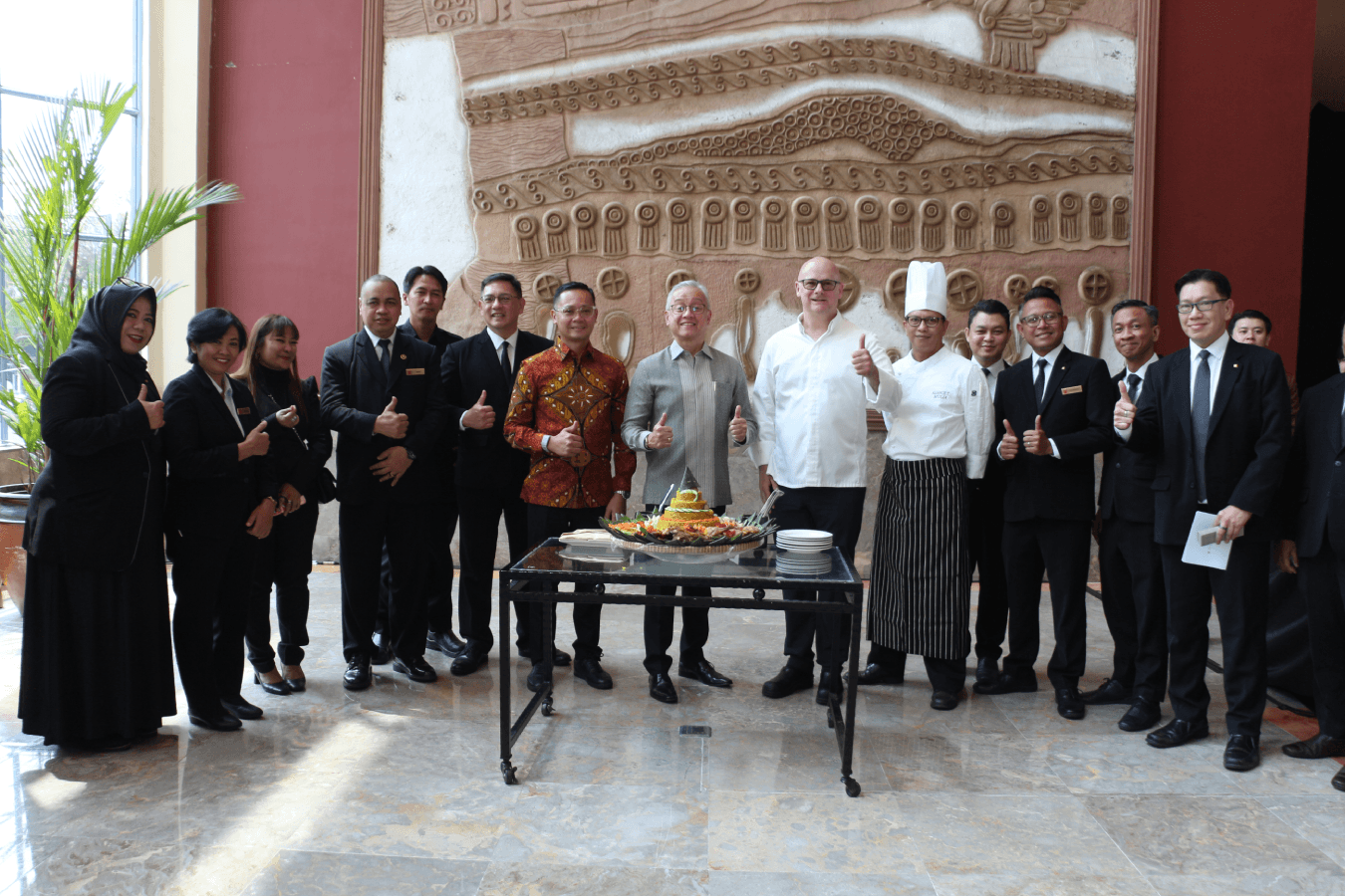 VIPs and the hotel team gather around the tumpeng to mark the reopening.