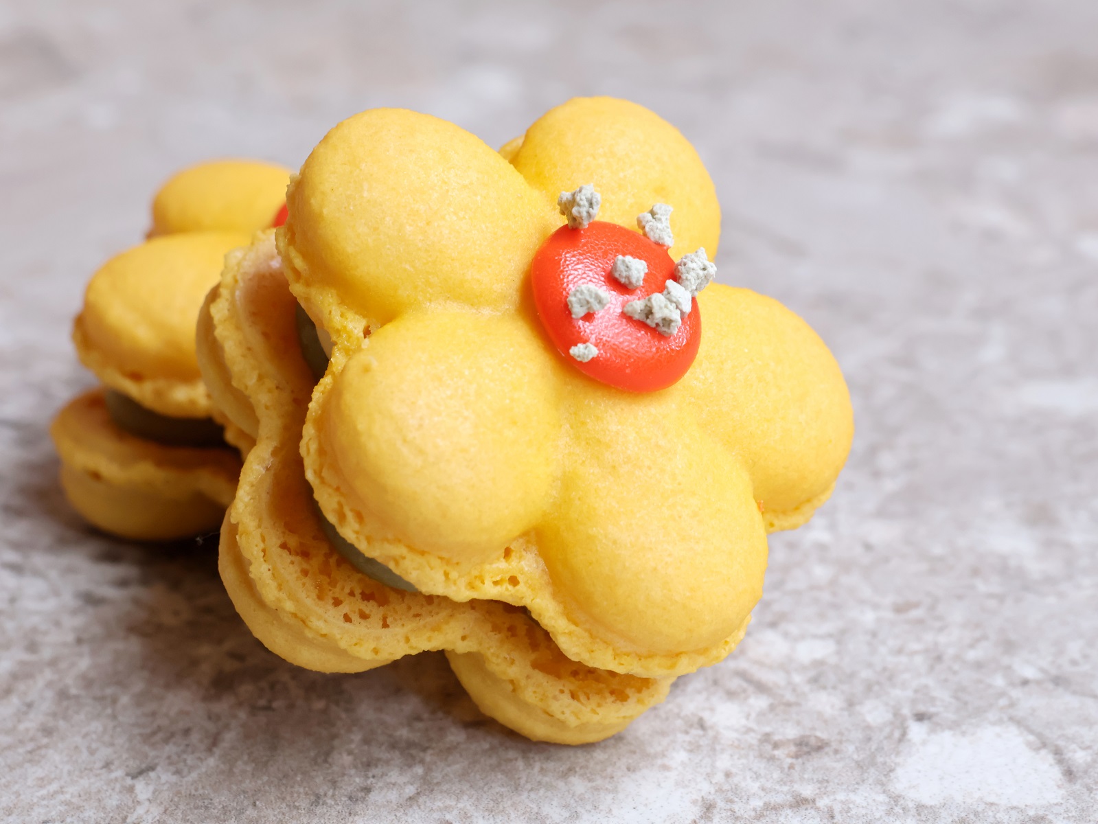The Yuzu Golden Lily Macaron, piped into the shape of a golden bloom.