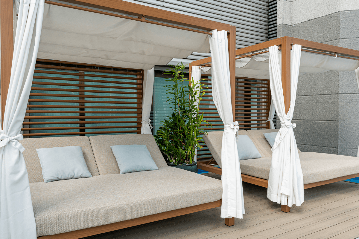 Curtained cabana daybeds beside the pool deck, set aside for quiet afternoons.
