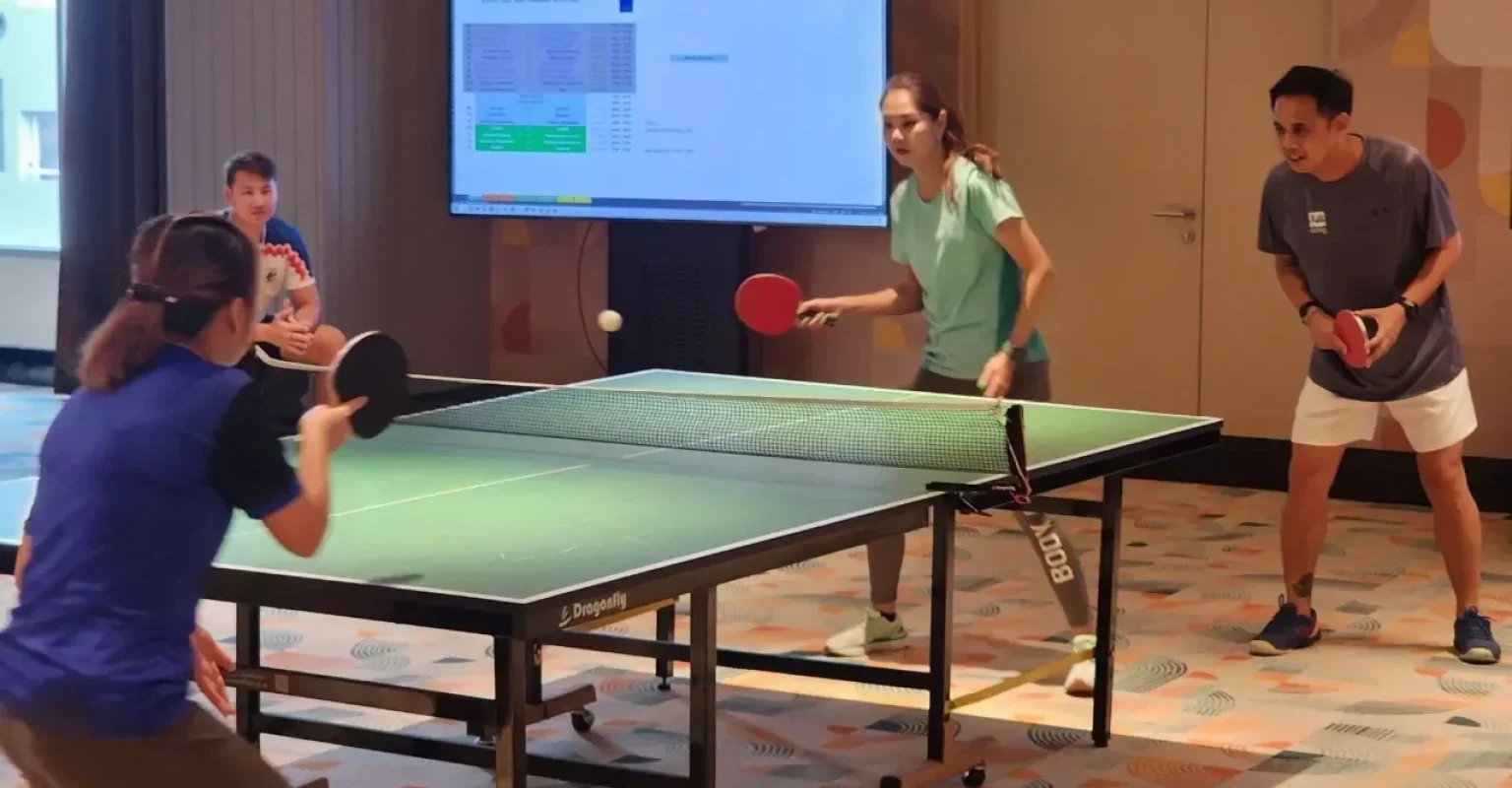 Buddies enjoying doubles table tennis, building team spirit through friendly competition